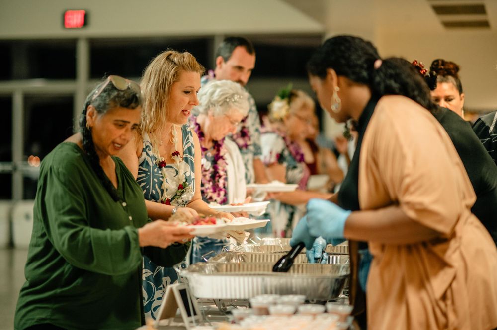 Guests serving themselves at a wedding buffet line.