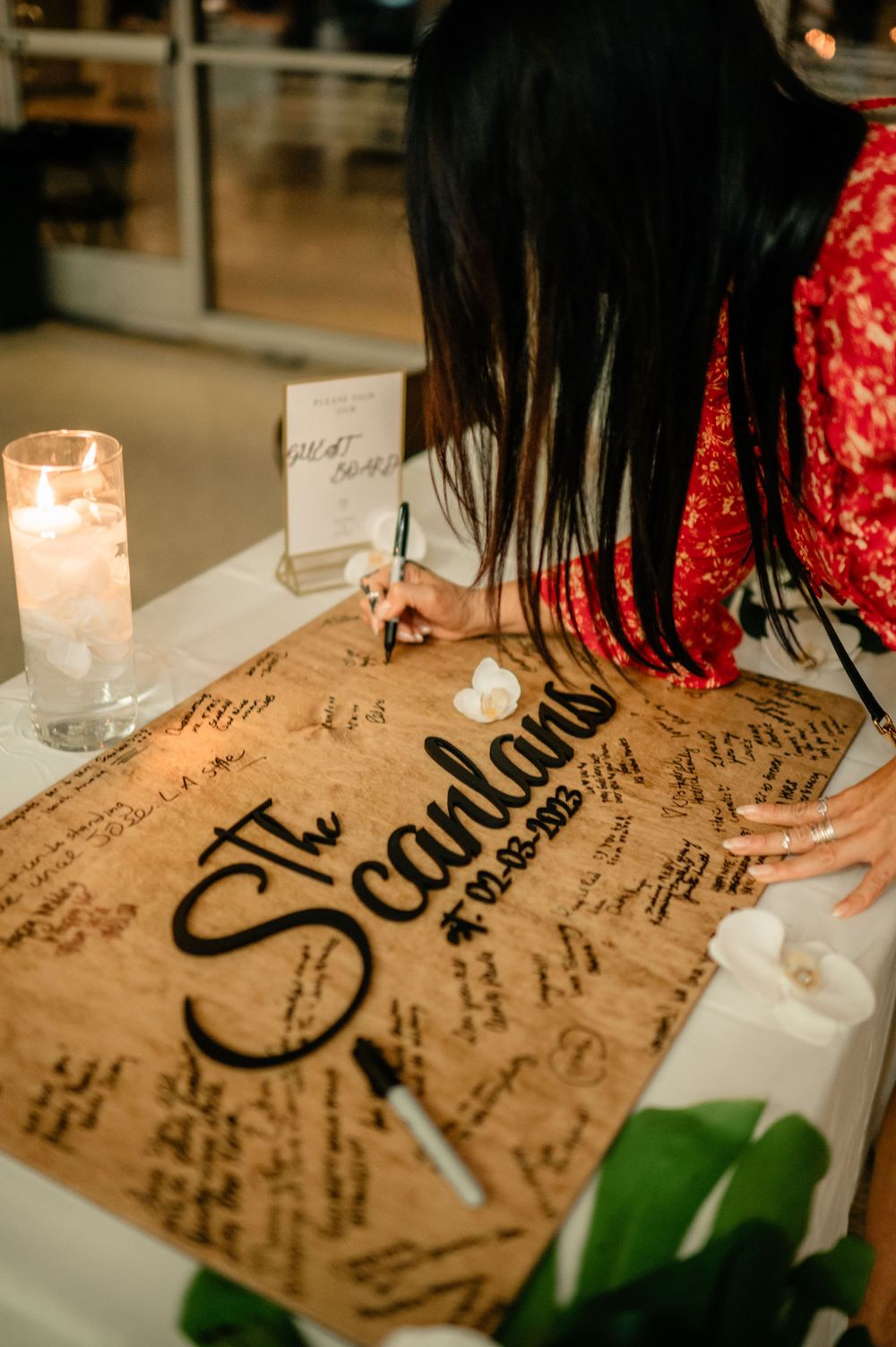 Wedding guest book with calligraphy and signatures surrounded by lit candles.