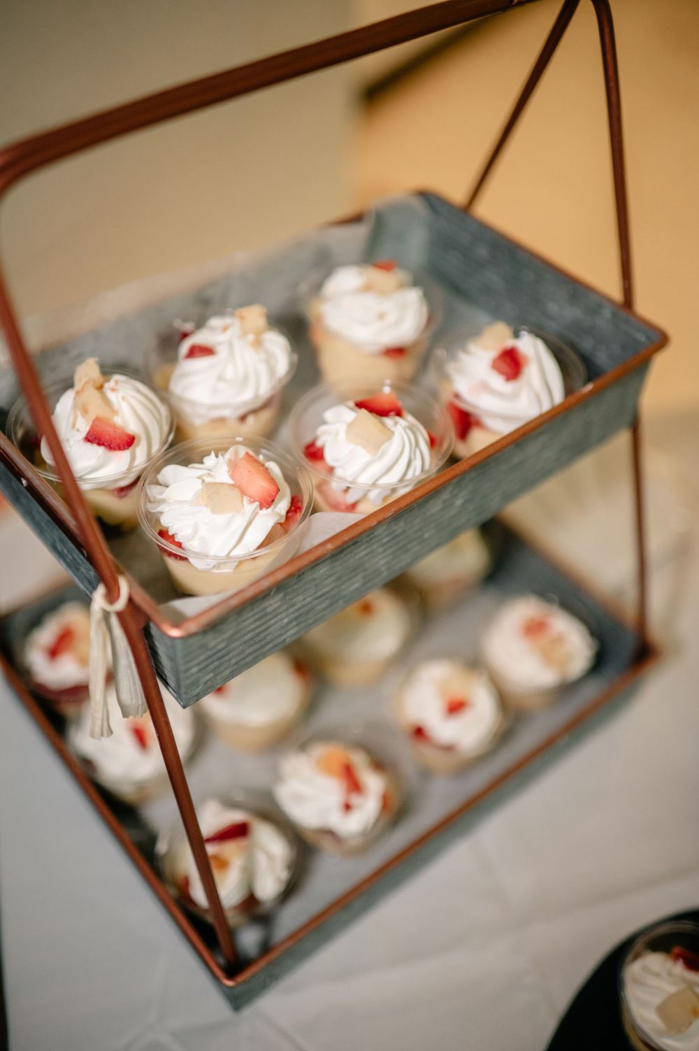 White meringue desserts with red cherry toppings displayed on tiered serving trays.