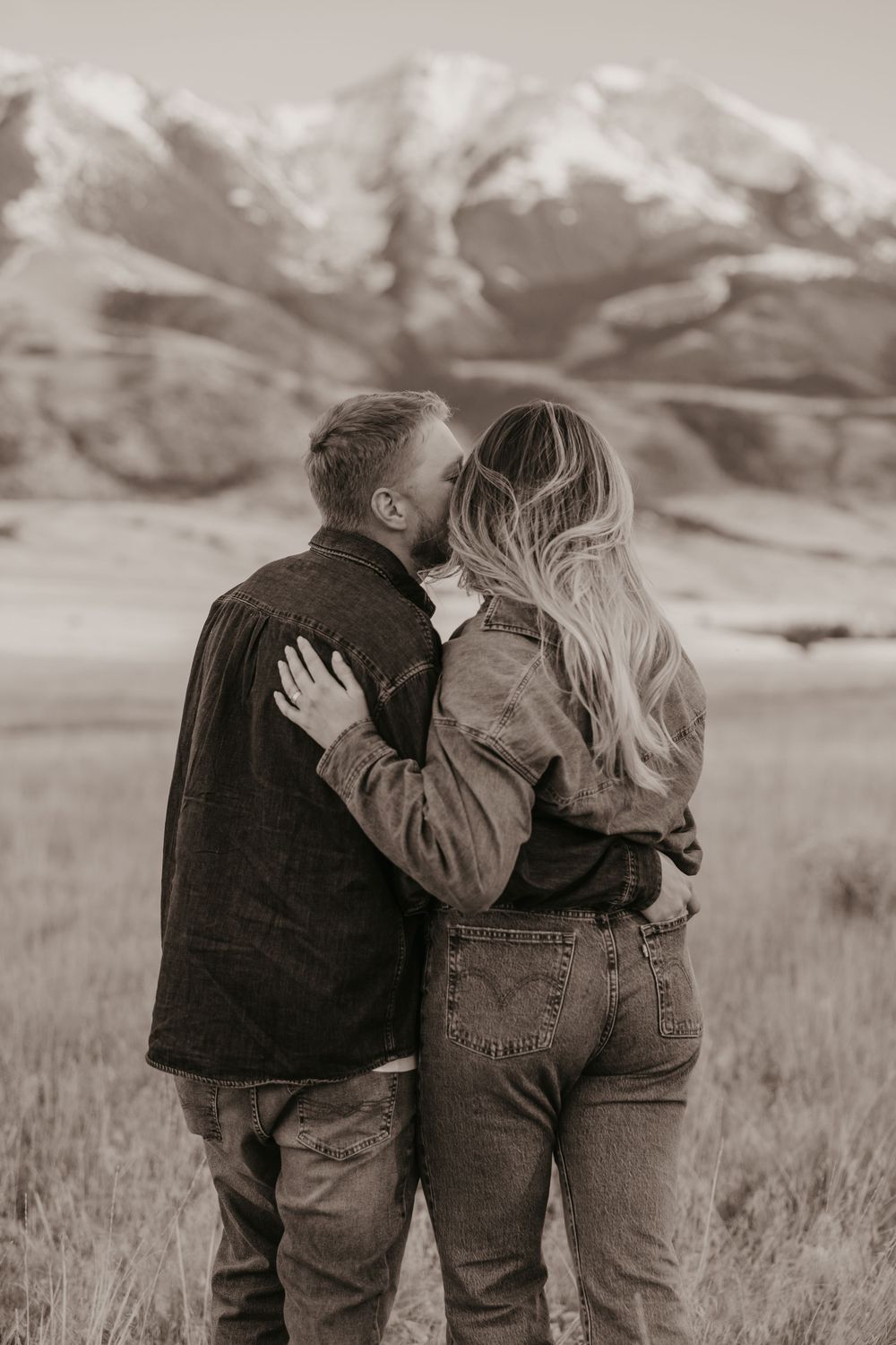 Montana photographer captures a couple embraced under the snow capped mountains near Livingston, Montana. Captured by western photographer.