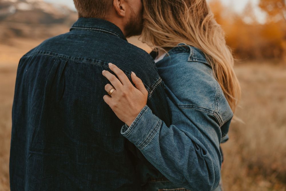 Paradise Valley couple embraces in warm fall of Montana, kissing her face and showing off her cigar band ring. Montana Wedding Photographer