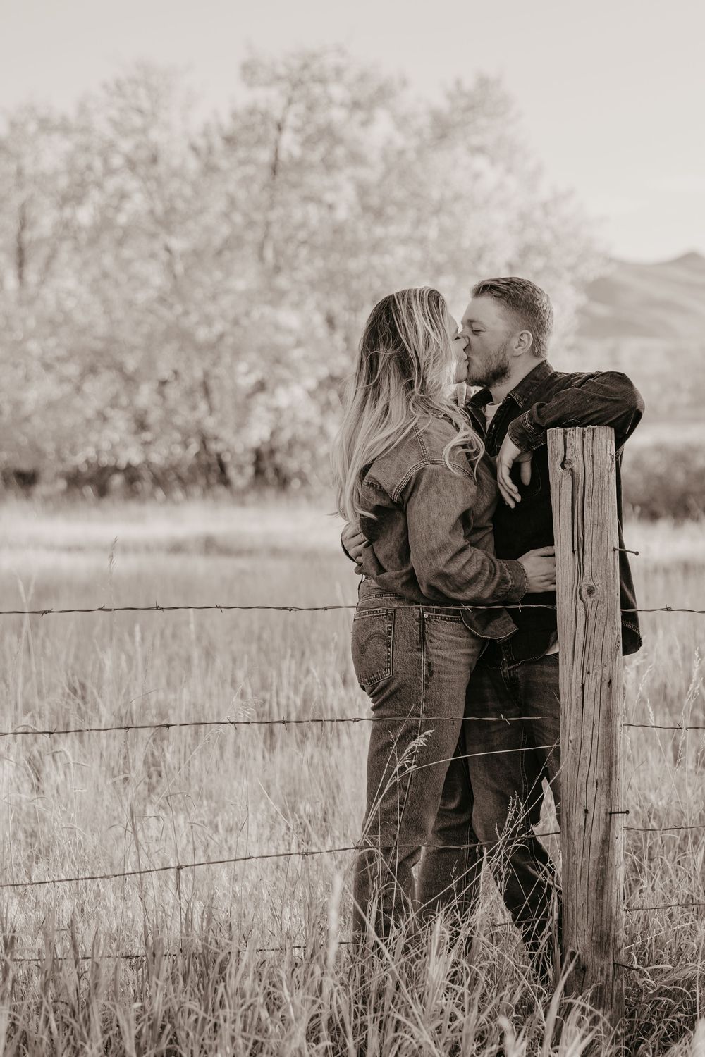 Western Engagement photos in Livingston, Montana captured by Sabrina Marie Photography leaning up against rustic fence.