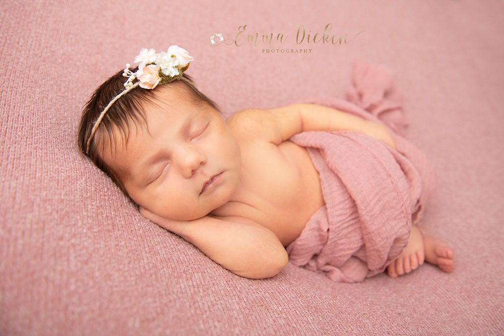 Newborn baby girl poses with flower headband photography in pink