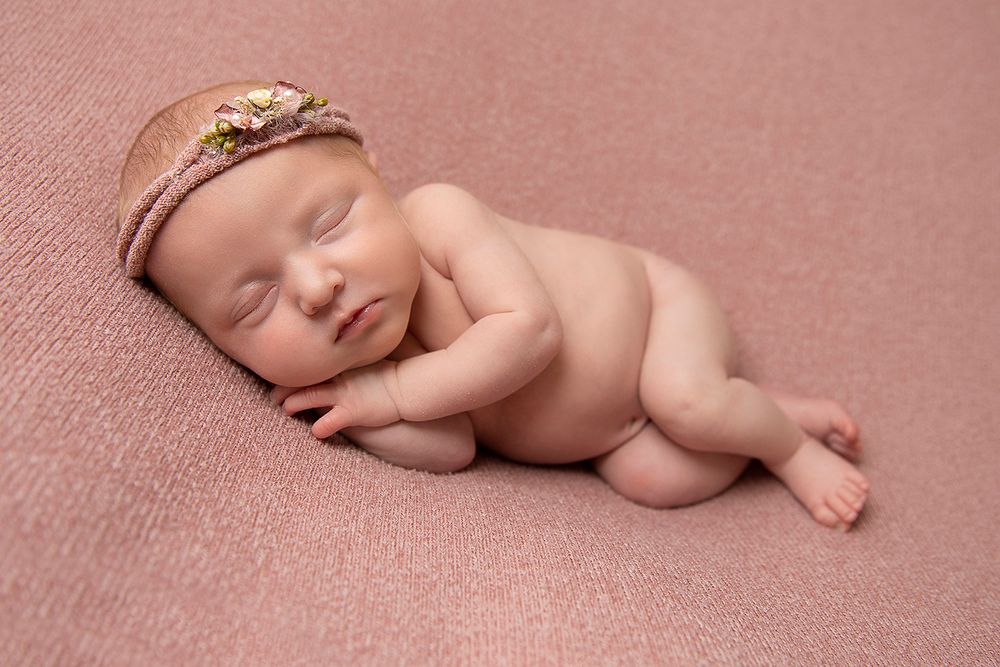 Newborn baby girl poses with flower headband photography in pink