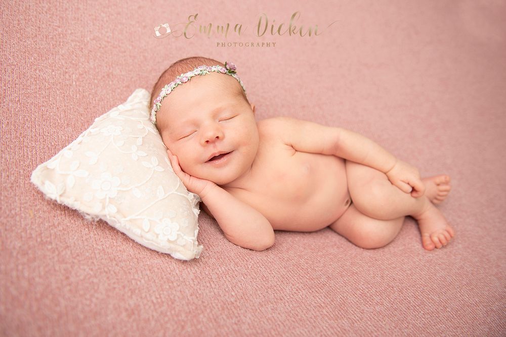 Newborn baby girl poses with pillow and headband