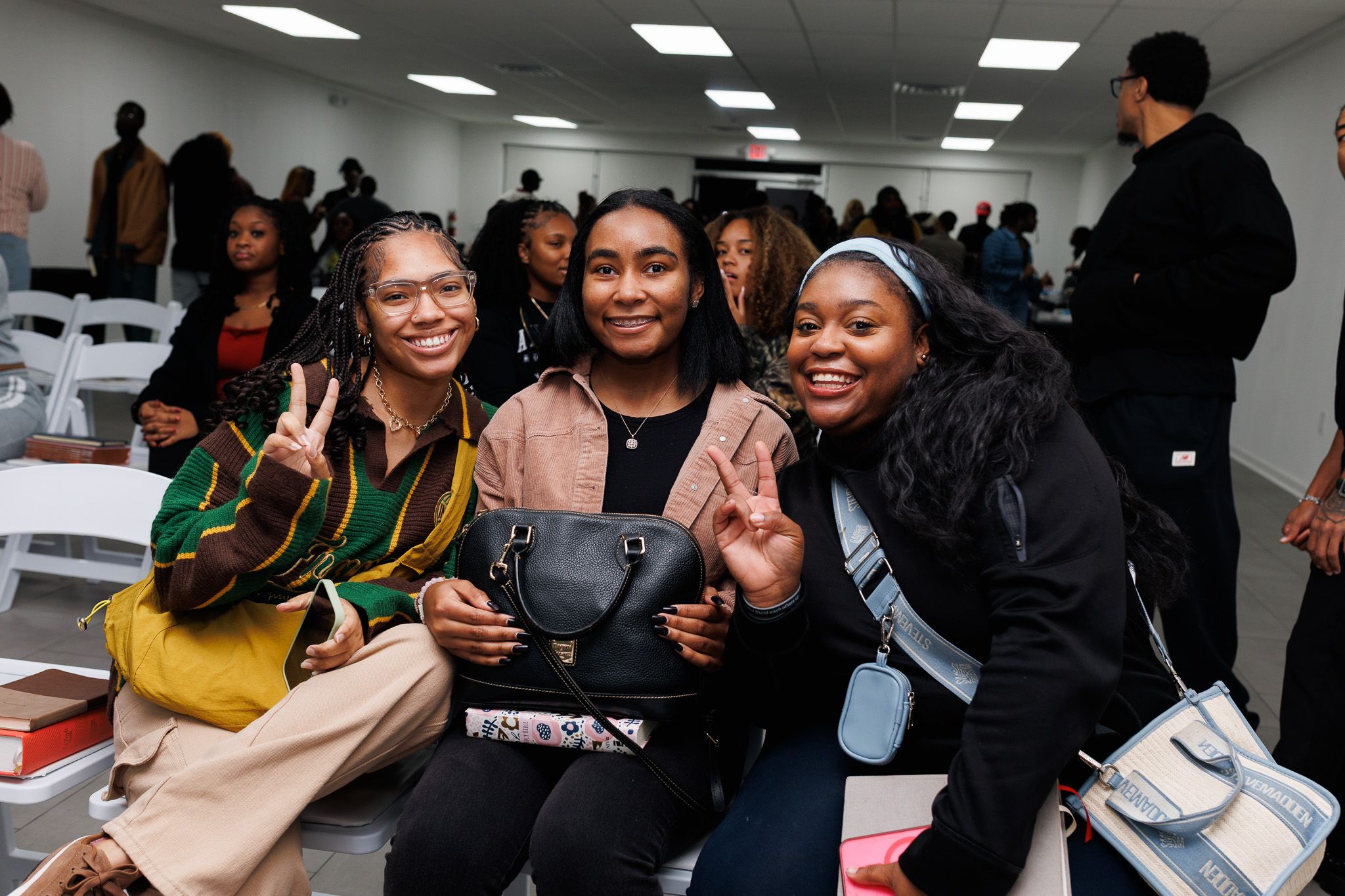 A group of people gather together in a bright office space sharing smiles and conversation during a social event.