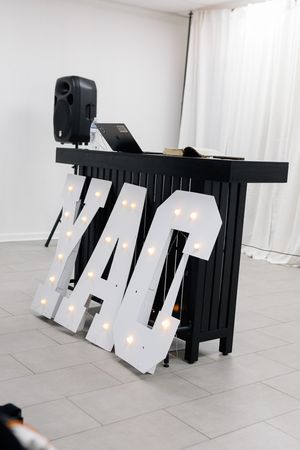 Black piano with illuminated white paper displays leaning against its base on a light gray tile floor.