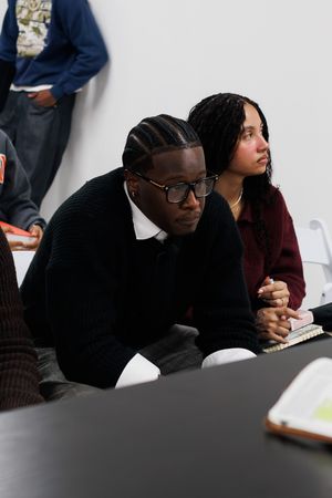 Students sitting at desks in a classroom while taking notes during a lecture or study session.