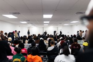 A crowded room filled with people sitting in chairs during what appears to be a conference or meeting.