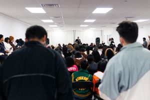 Diverse crowd of people gathered in a bright indoor space for an event.