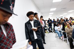 Long hallway filled with students waiting in line against white walls and fluorescent lighting.