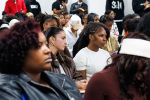 Group of attendees sitting and standing in rows during an indoor gathering.