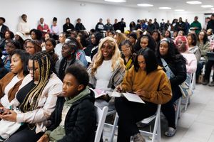 A crowded room filled with students sitting in rows of chairs during what appears to be a presentation or lecture.
