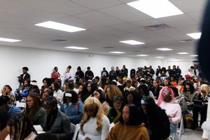 Large crowd of students gathered in a bright classroom or meeting space for an event or presentation.