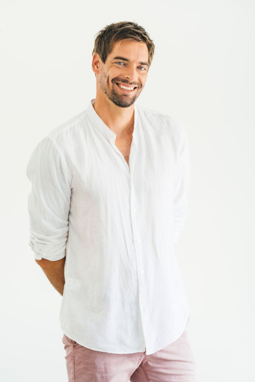 Professional wearing a bright blue blazer and white shirt stands confidently in an elegant hallway with white walls.