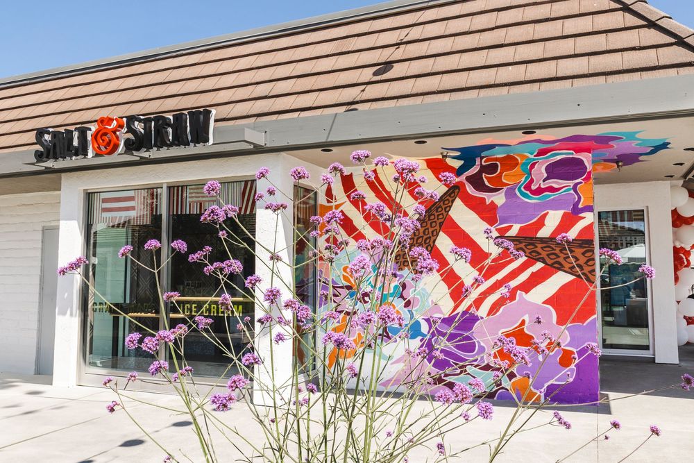 Colorful koi fish windsocks and decorative flags wave in the breeze outside a traditional cedar-shingled storefront.
