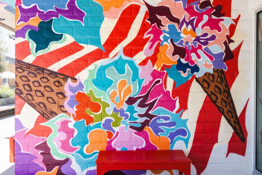 Vibrant abstract mural featuring colorful swirls, patterns and shapes painted on a wall in bold red, blue, and purple tones.