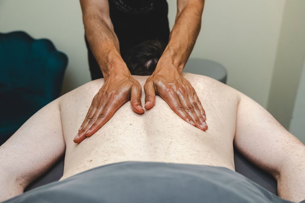 A series of hands demonstrating a back massage technique on a person lying on a massage table.