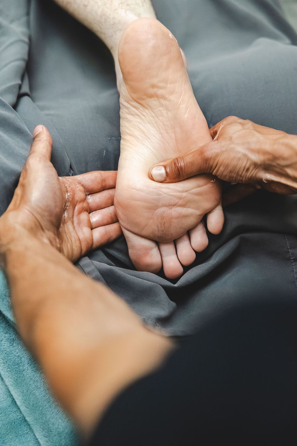 Close-up sequence of hands performing therapeutic massage techniques on feet against dark background.