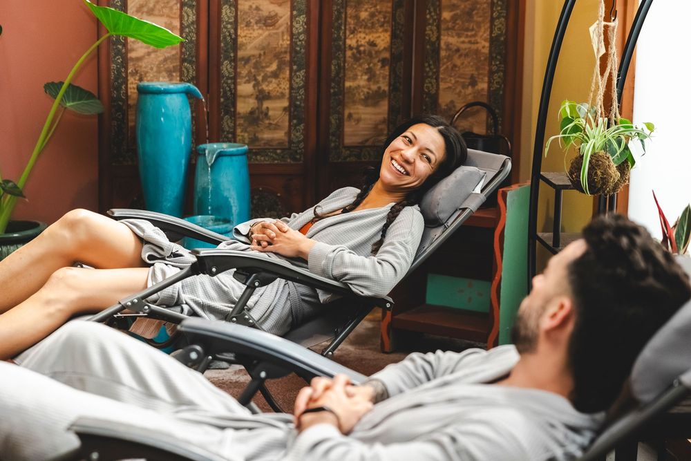 Person relaxing in bed with houseplants visible in the background creating a cozy bedroom atmosphere.