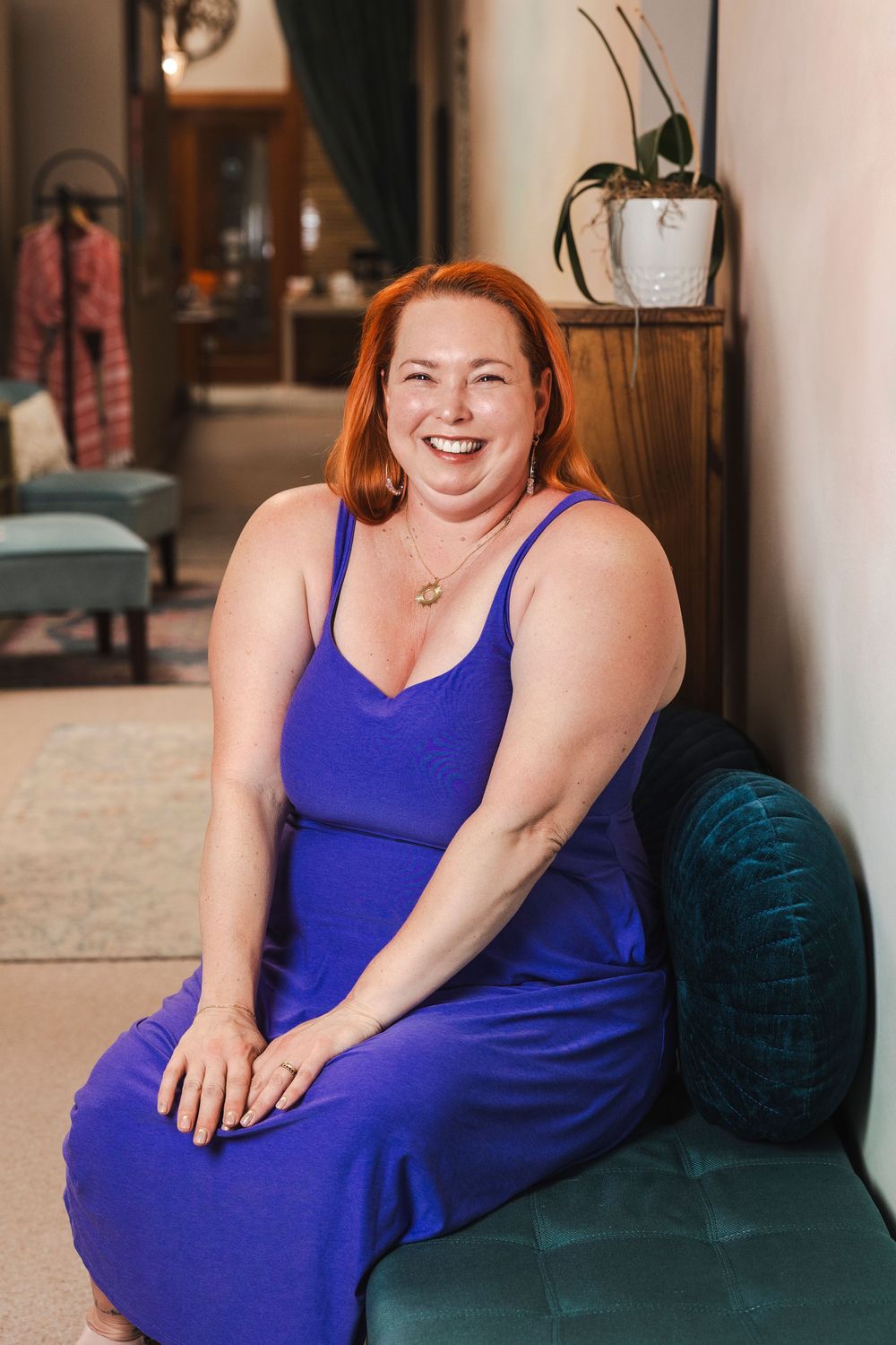 Person in bright blue dress sitting comfortably on dark couch in home setting.