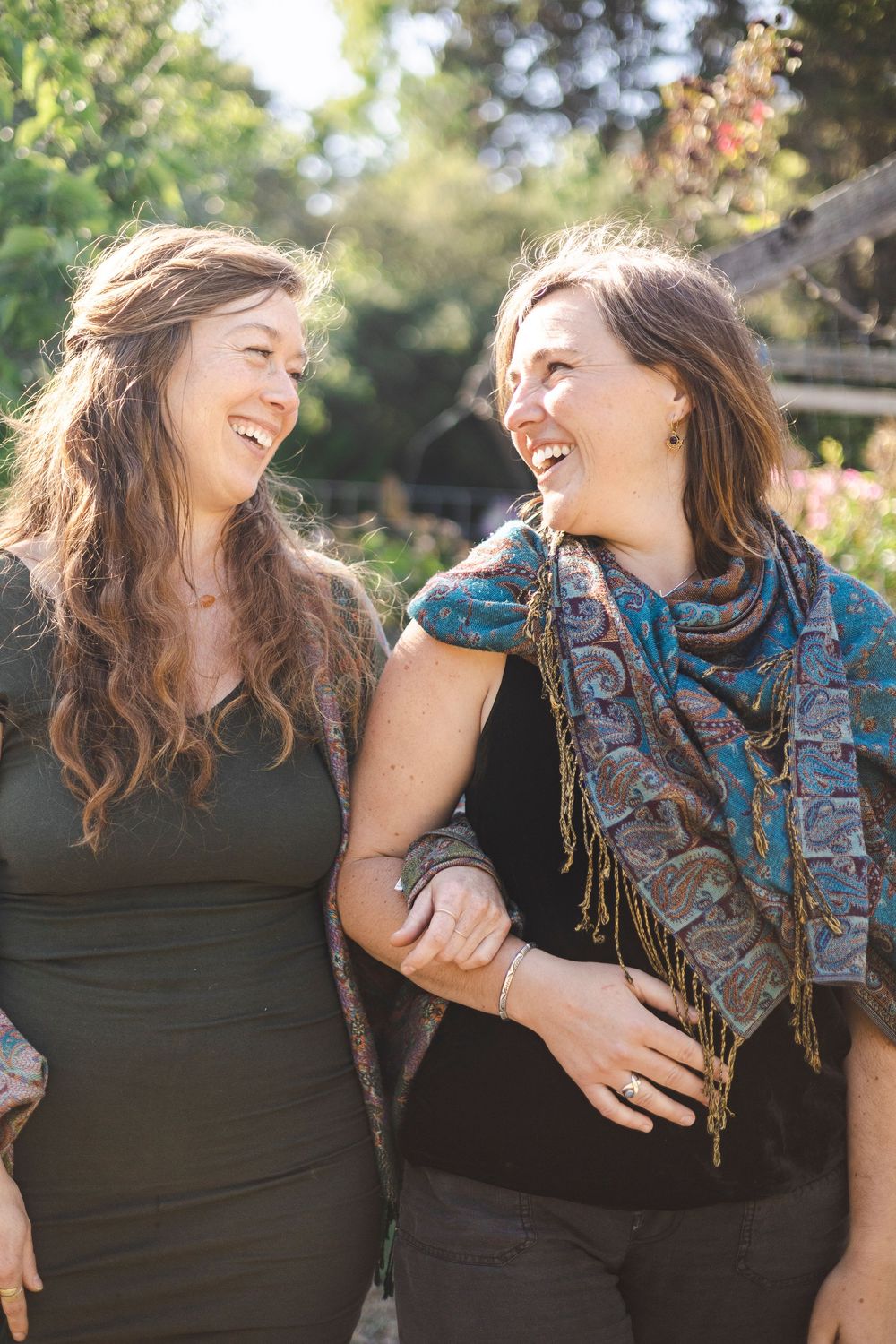 Two friends sharing a joyful moment outdoors, laughing together in natural sunlight.