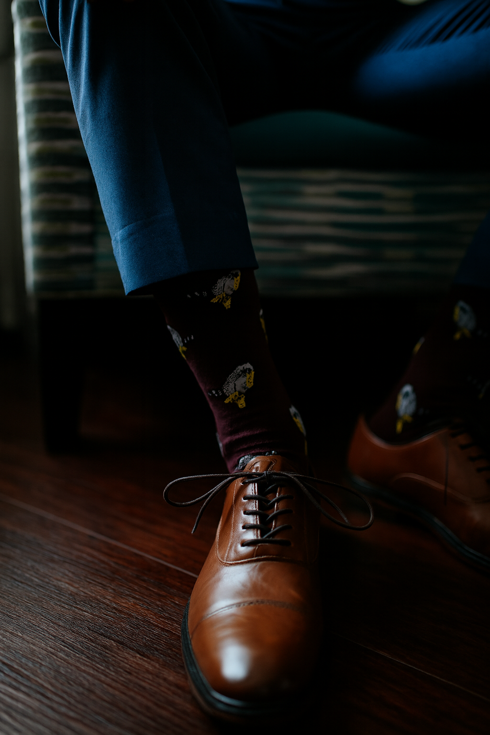 Brown leather oxford shoes shown in a sequence of motion on dark wooden flooring.