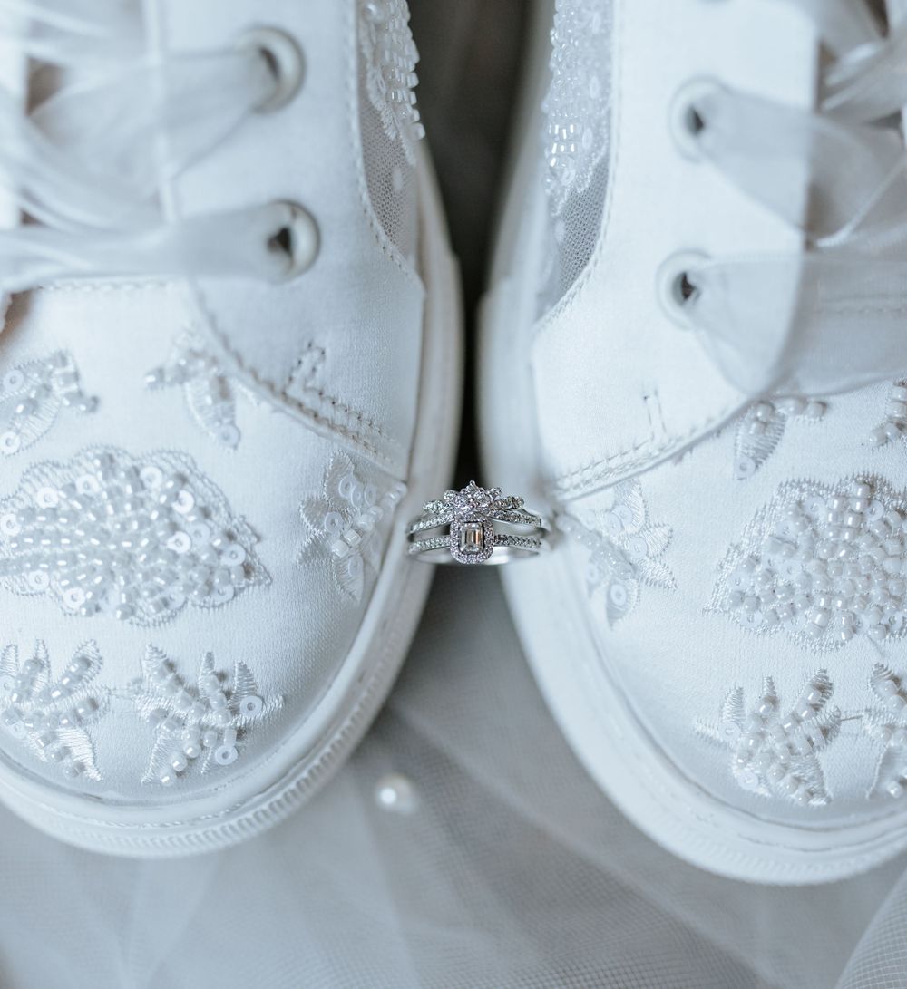 Close-up of white bridal sneakers decorated with delicate beading and pearls.