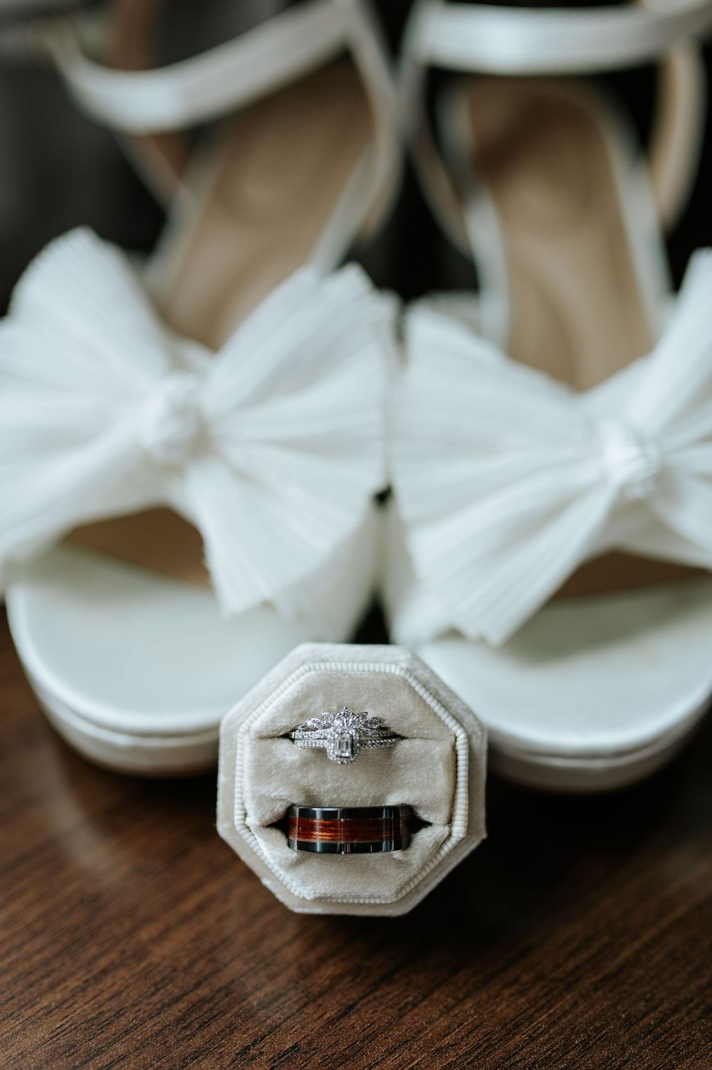 Wedding rings displayed in elegant silver ring boxes on a wooden surface.