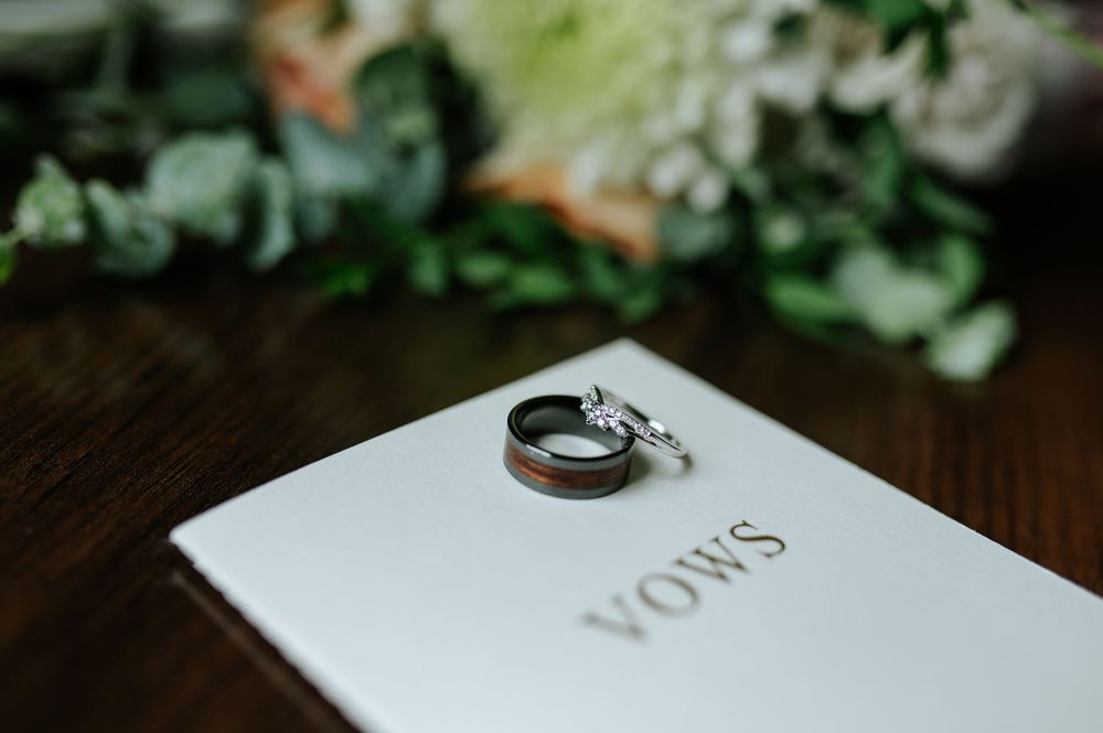 Wedding rings photographed with greenery and white floral decorations.