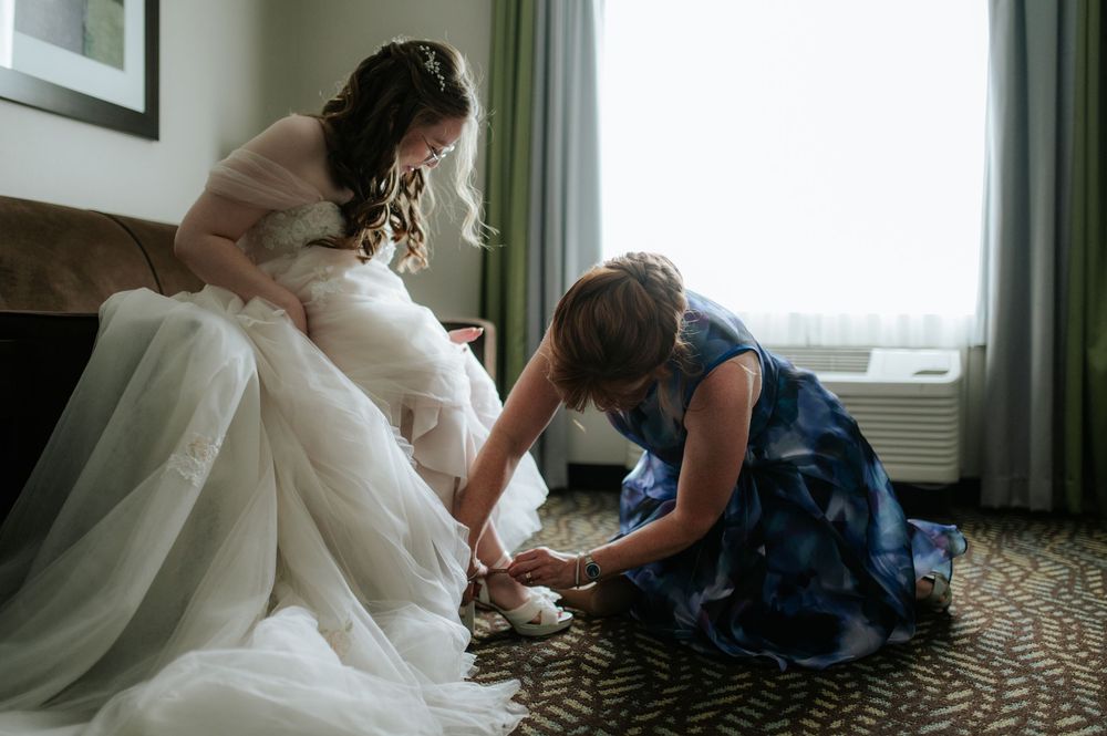 Wedding dress preparations with attendants helping adjust the gown.