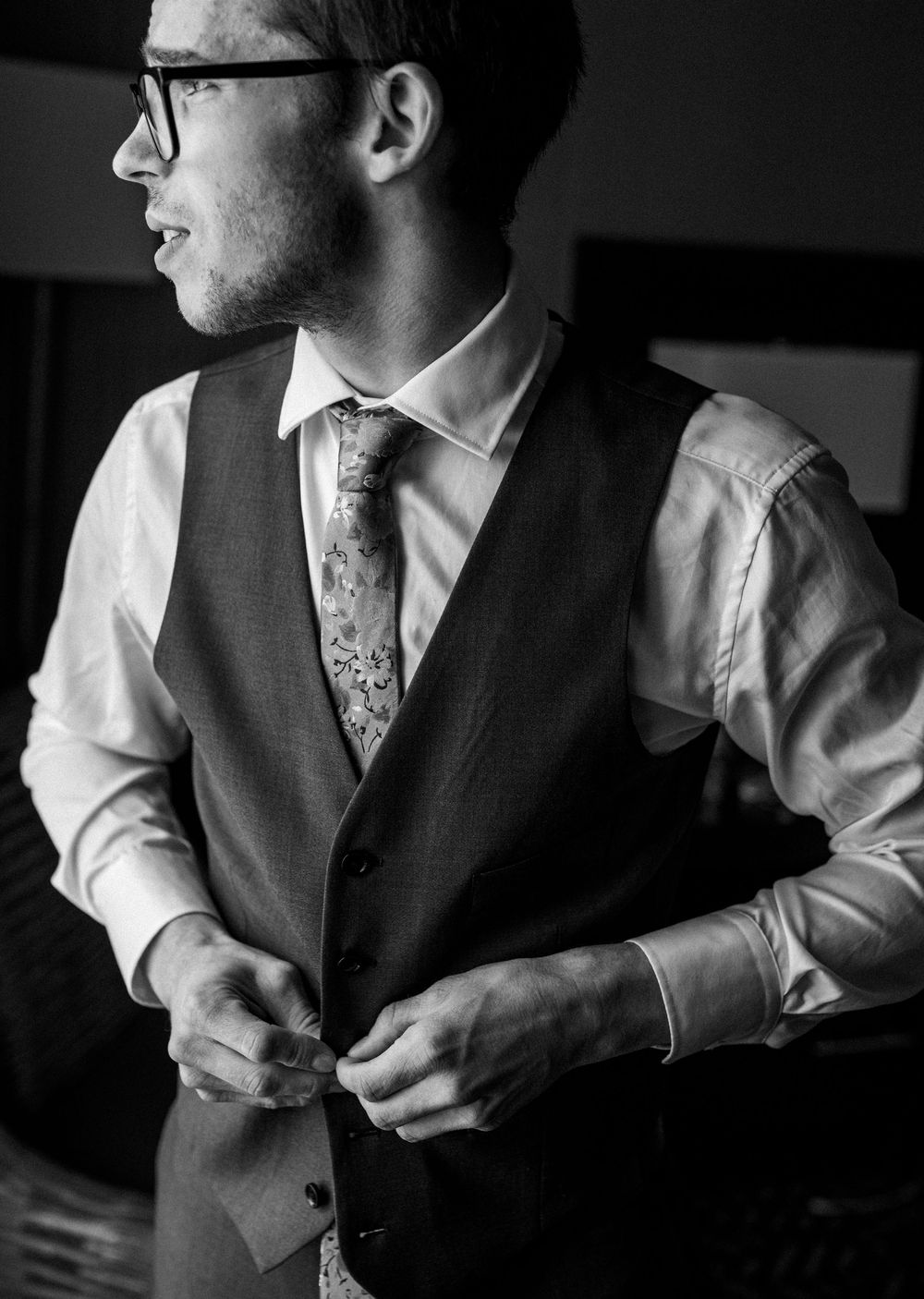 Black and white close-up shots showing details of a groom getting dressed in formal wedding attire.