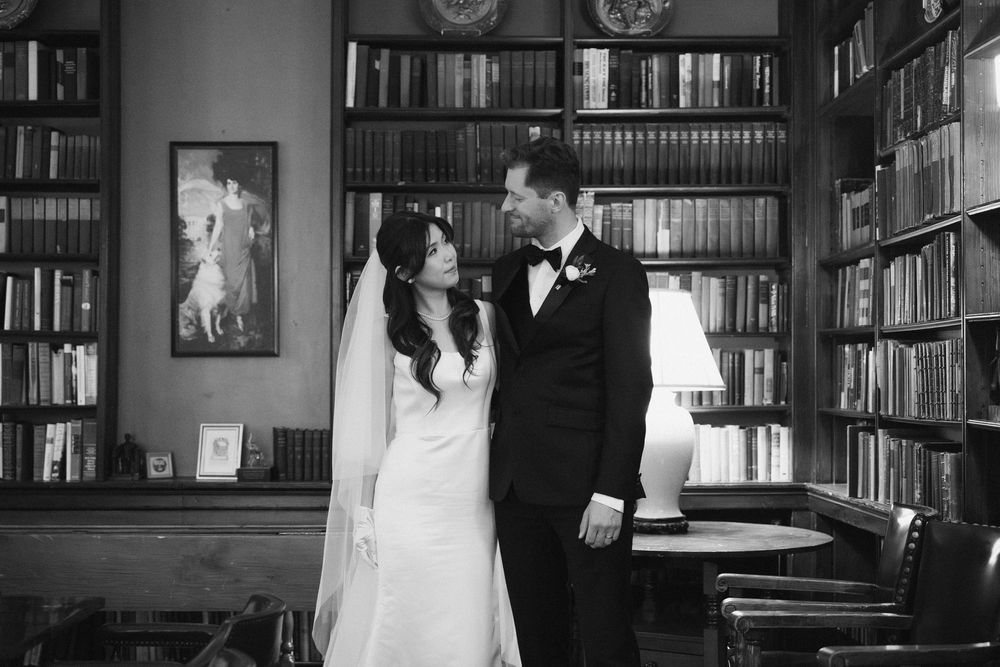 Wedding ceremony taking place in a traditional library with book-lined walls.