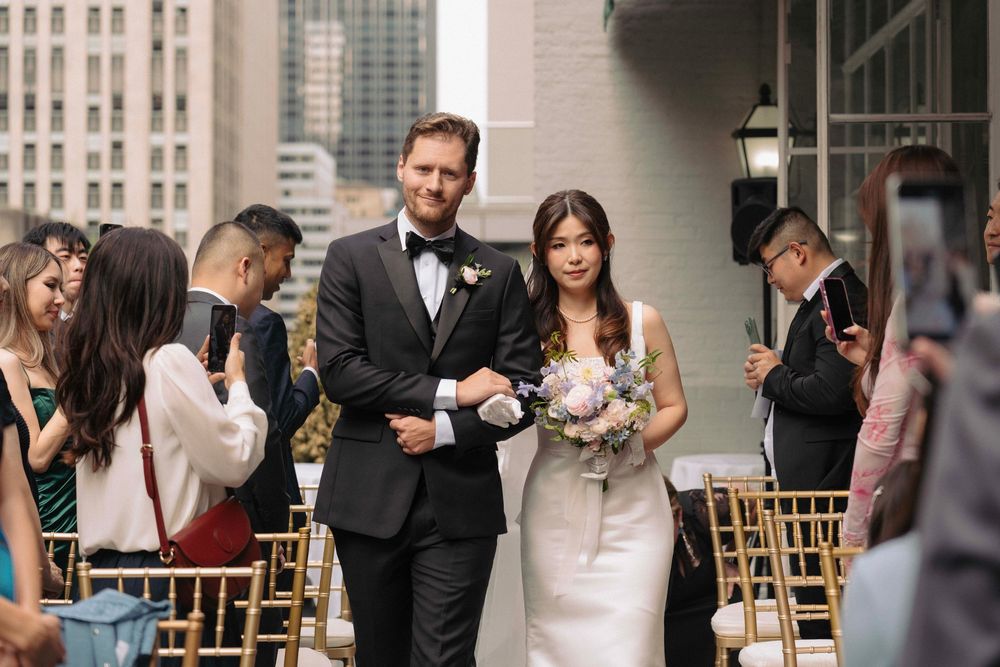 Wedding party gathered on an urban rooftop with city buildings in the background.