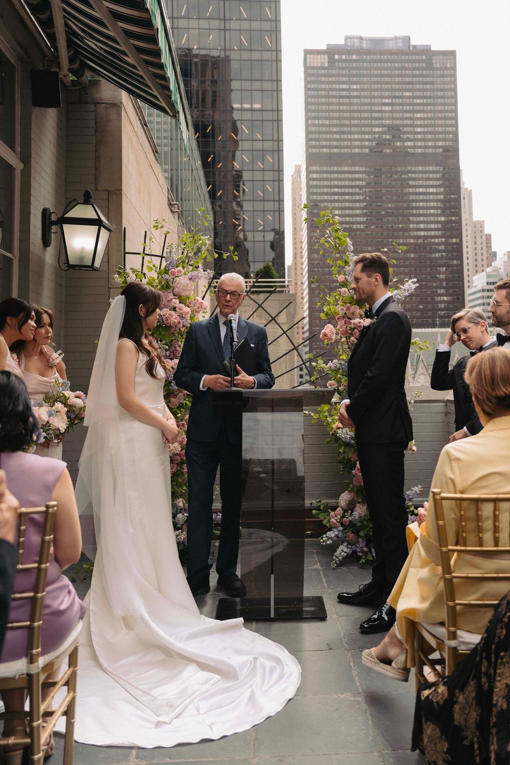Rooftop wedding ceremony with Manhattan skyline and gold chairs in the background.