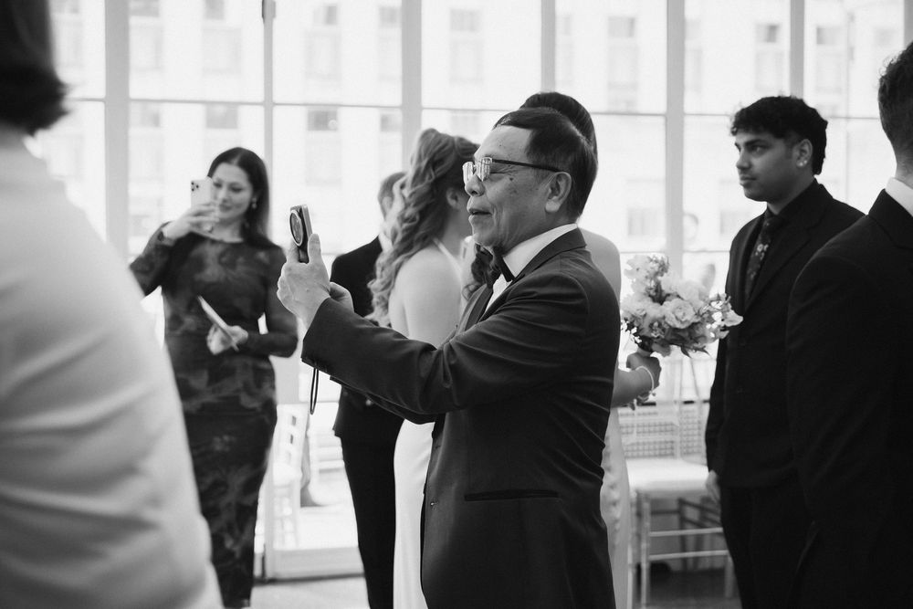 Wedding guests in formal attire mingling during reception in bright indoor space.