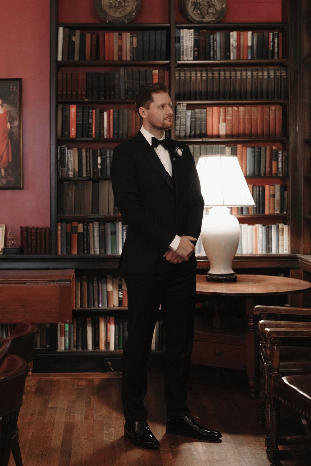 Formal event in a library with dark wood bookshelves and red walls.