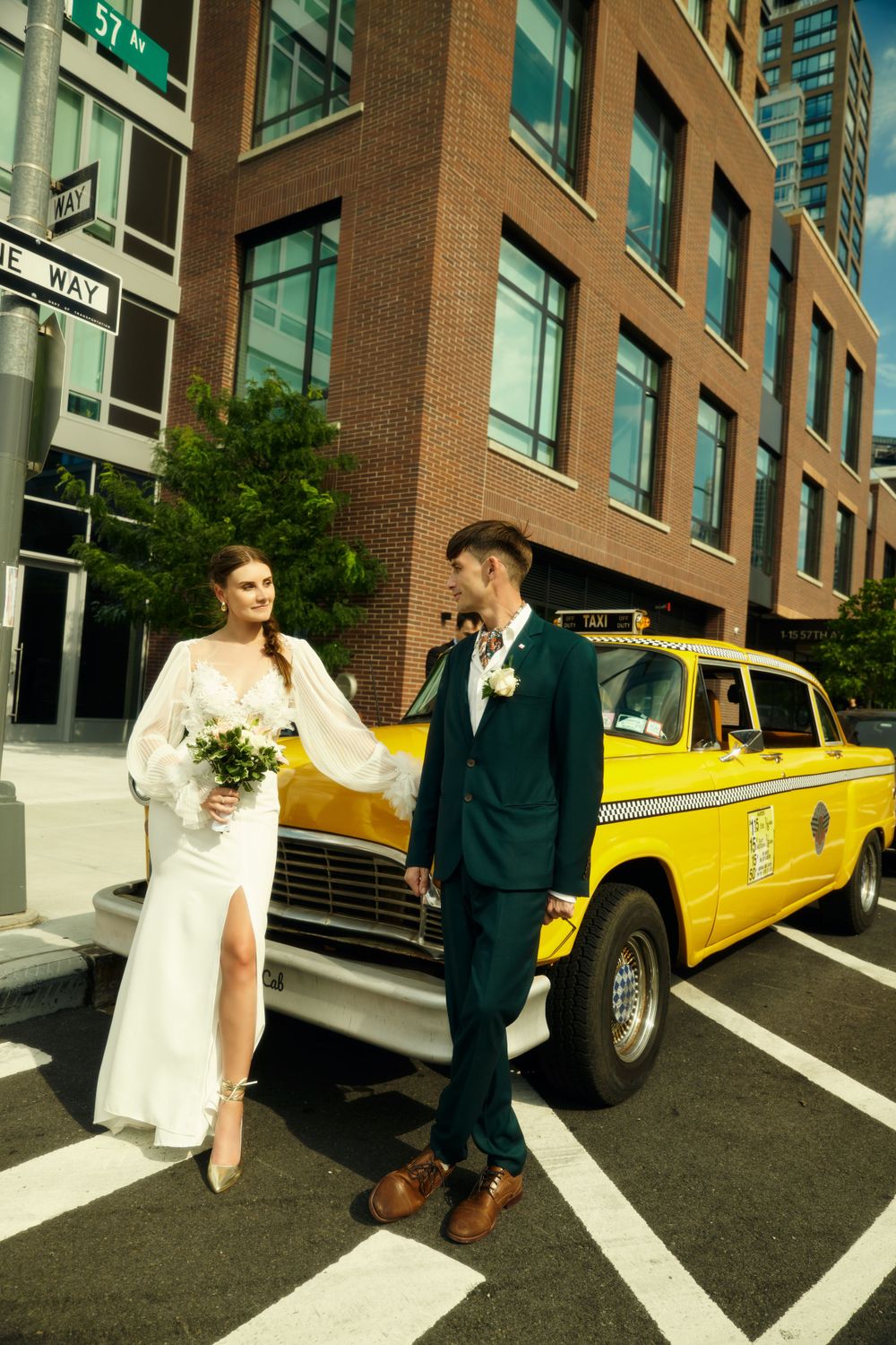 Wedding couple poses by yellow NYC taxi cab on city street.