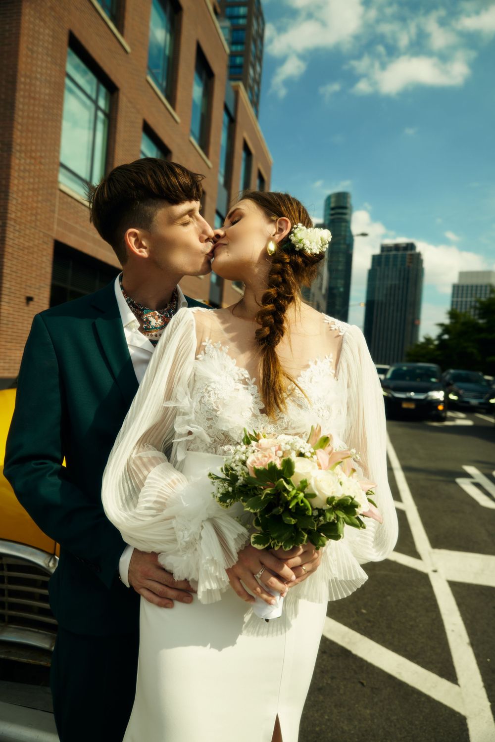 Newlyweds share tender moments near a yellow taxi in an urban setting.
