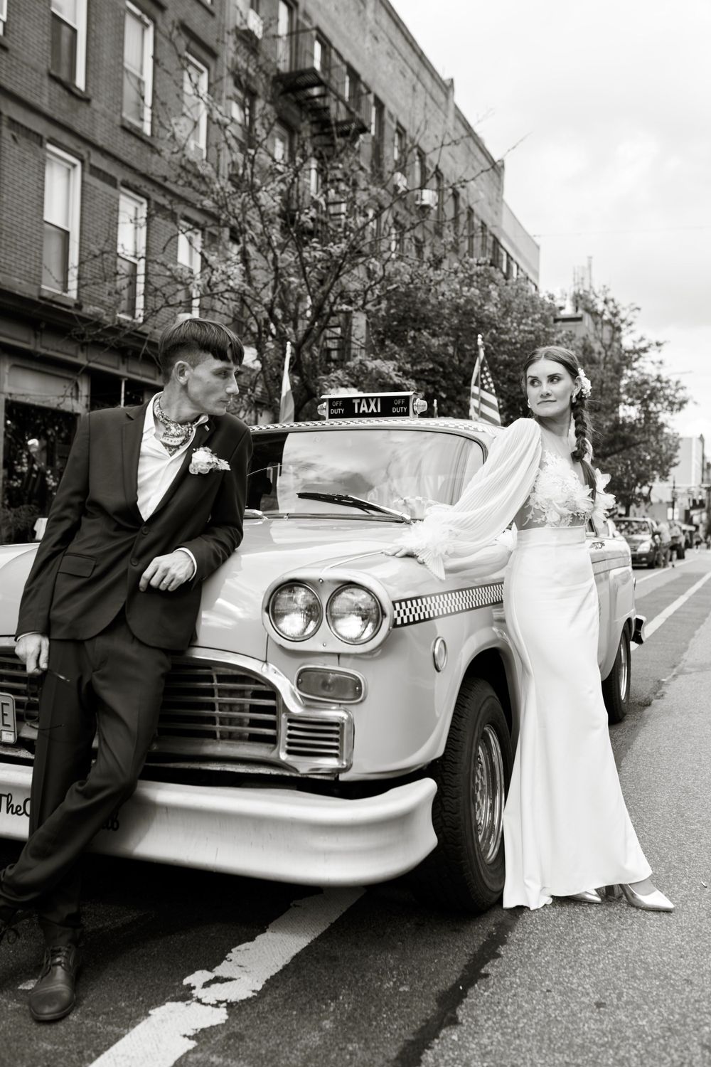 Retro-styled wedding photo with classic taxi and couple in black and white.