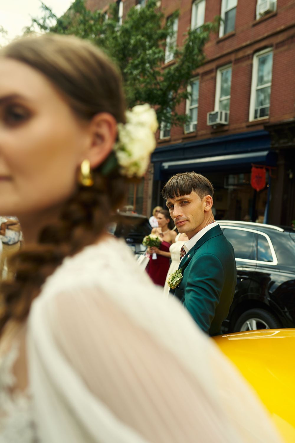 Artistic wedding portrait featuring couple and yellow taxi in urban setting.