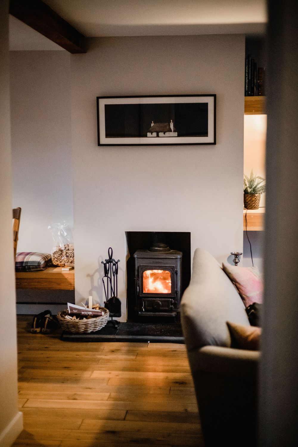 Cozy living room corner with wood burning stove, hardwood floors, and framed artwork.