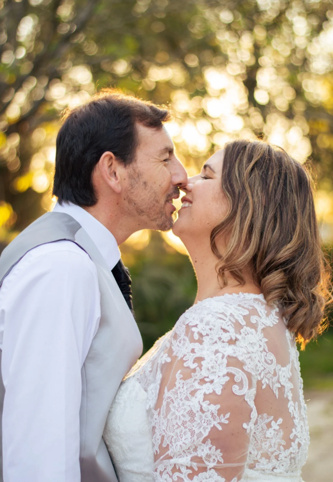A tender moment between newlyweds in elegant wedding attire during golden hour.