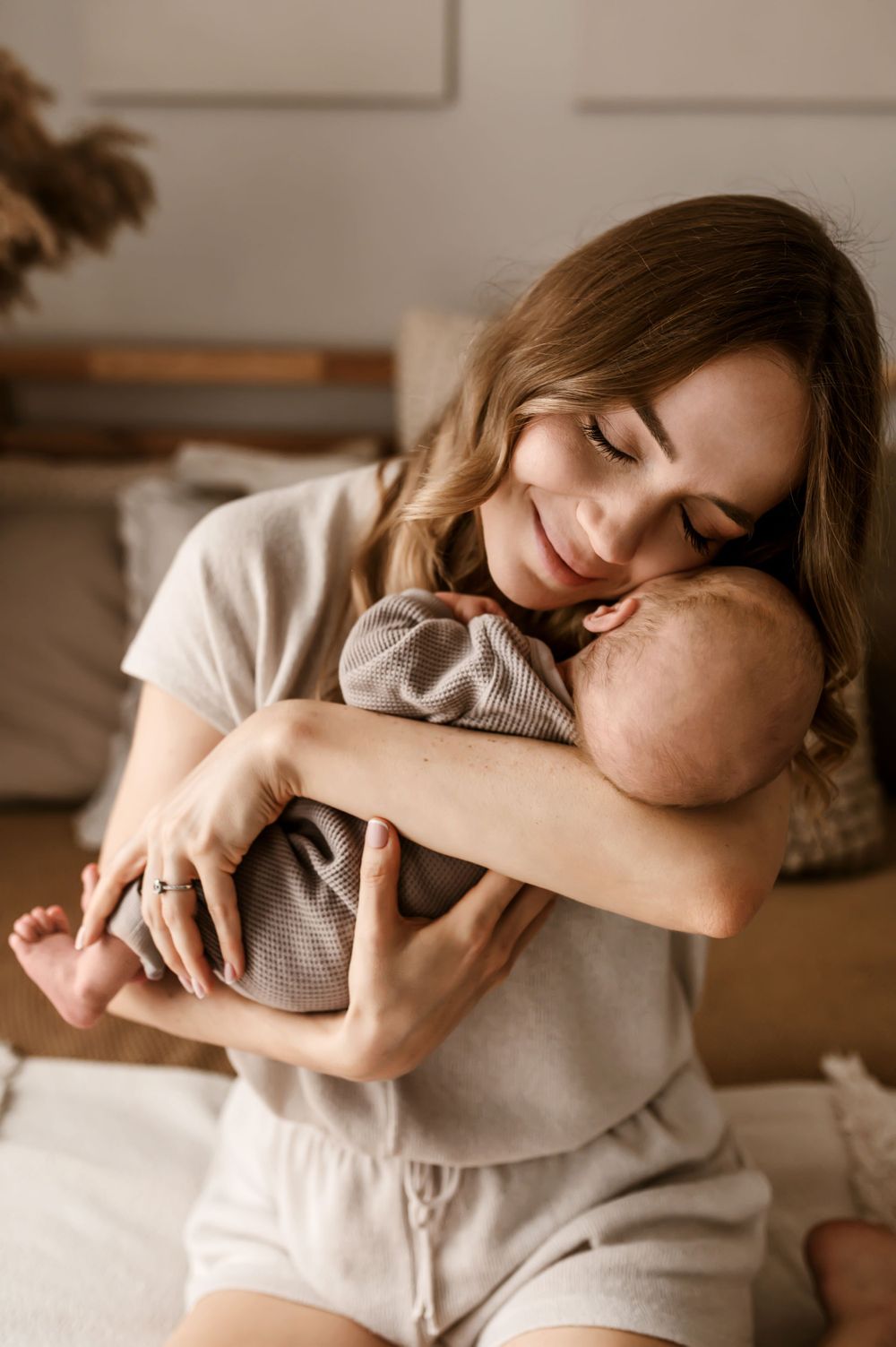 A tender moment of parent embracing their sleeping infant in cozy home setting with warm lighting.