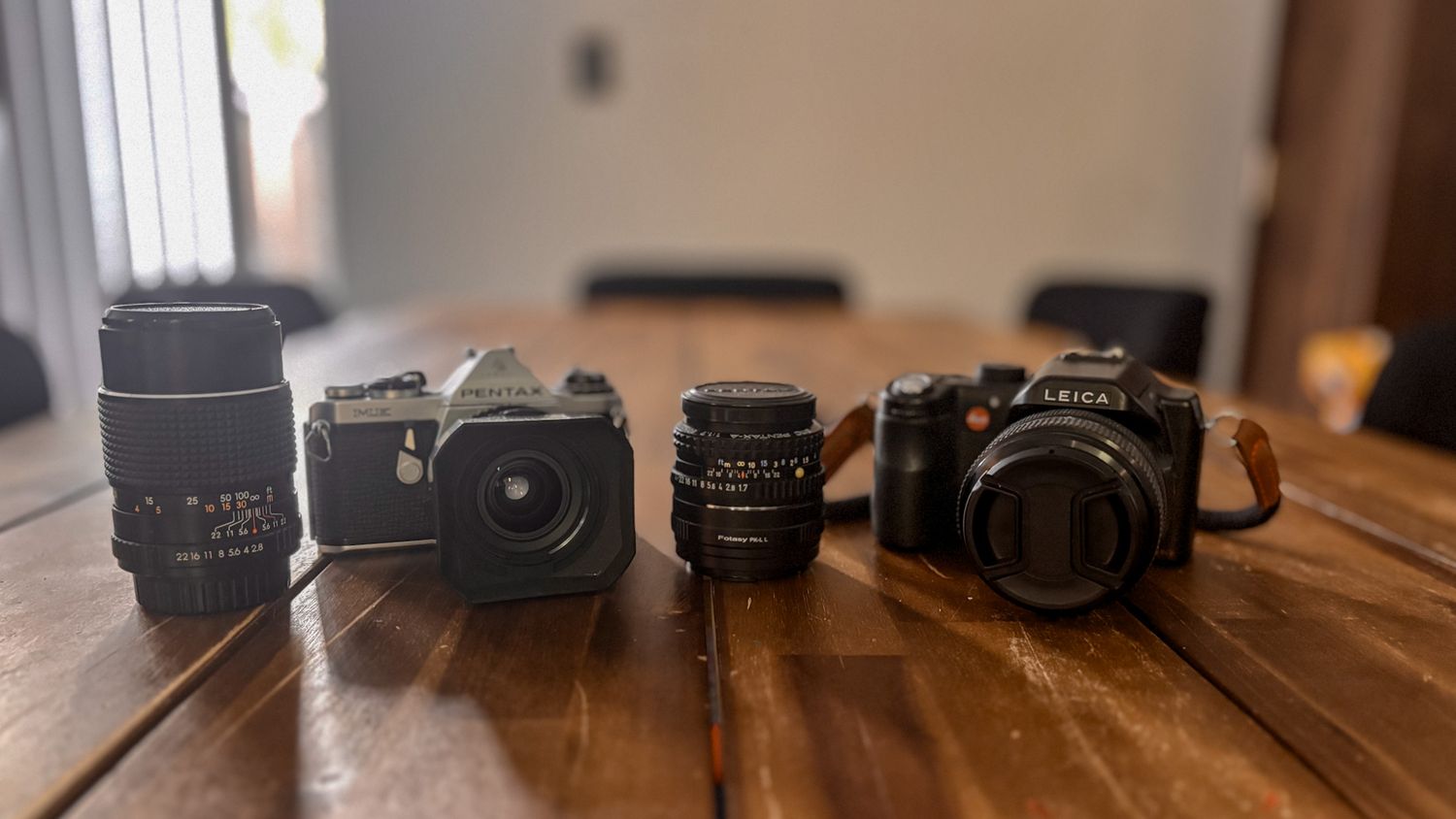 Collection of classic cameras and lenses displayed on wooden tabletop.