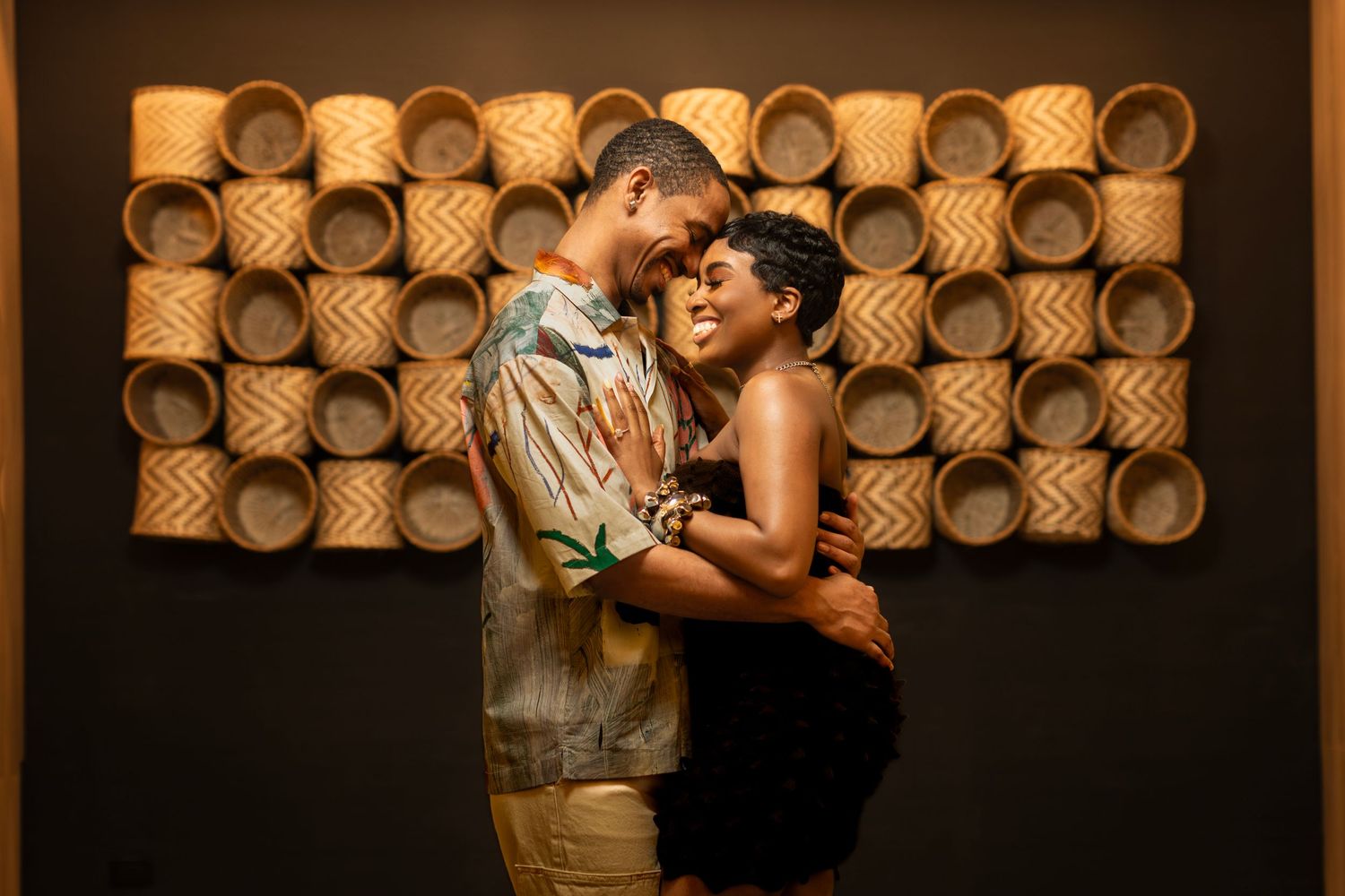 Intimate couple portrait with decorative woven basket wall backdrop.