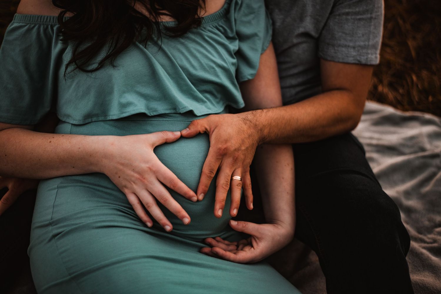 Close-up of hands with engagement ring resting on leg in intimate moment.