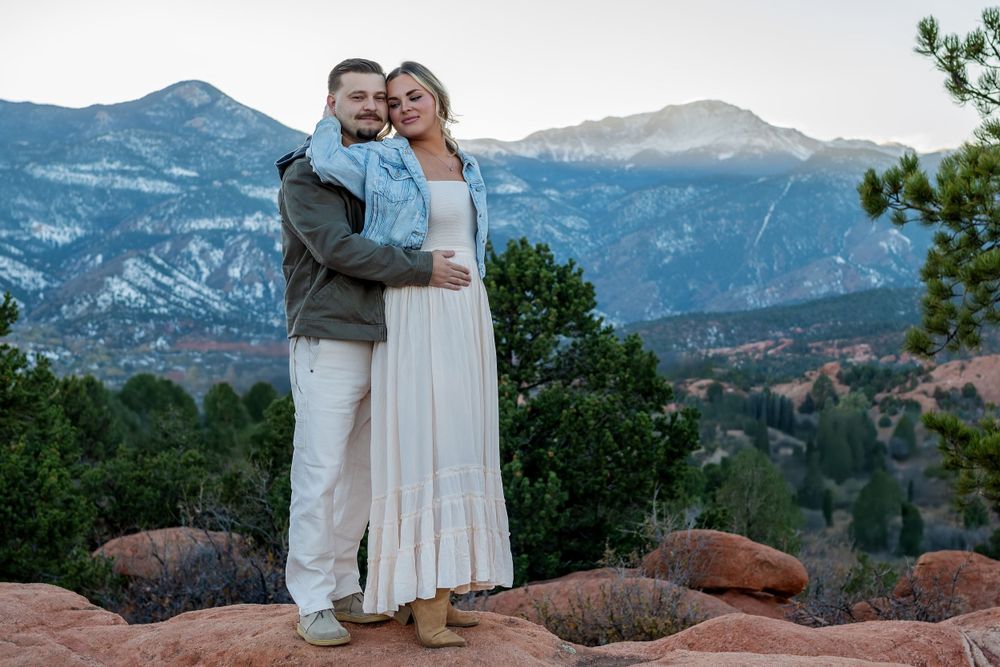 A couple poses together against a scenic mountain backdrop at Garden of the Gods in Colorado.