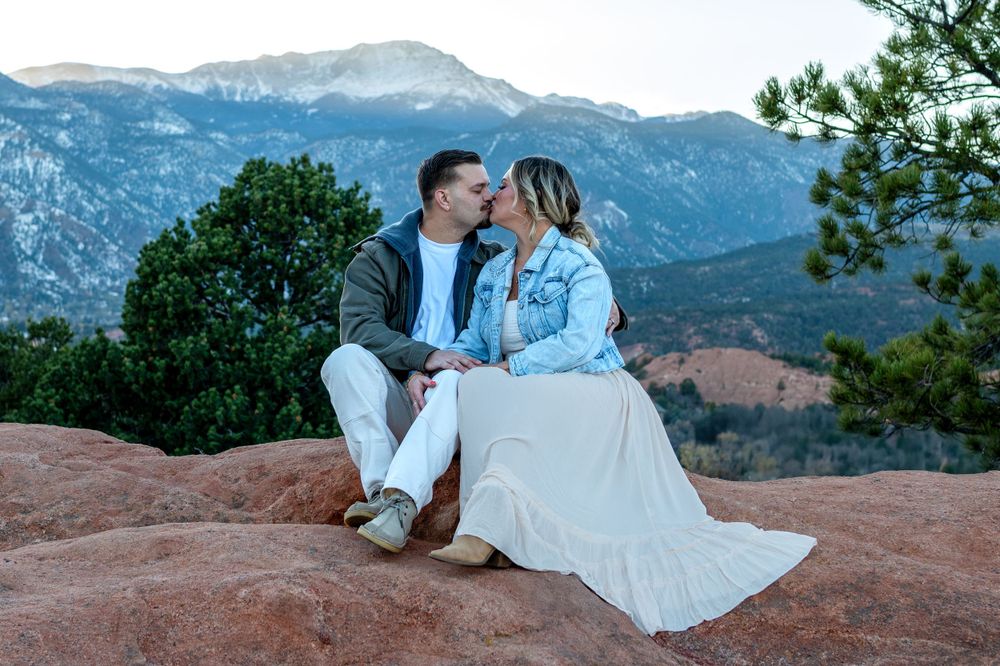 Romantic moment captured on red rocks with mountains in the distance at Garden of the Gods.
