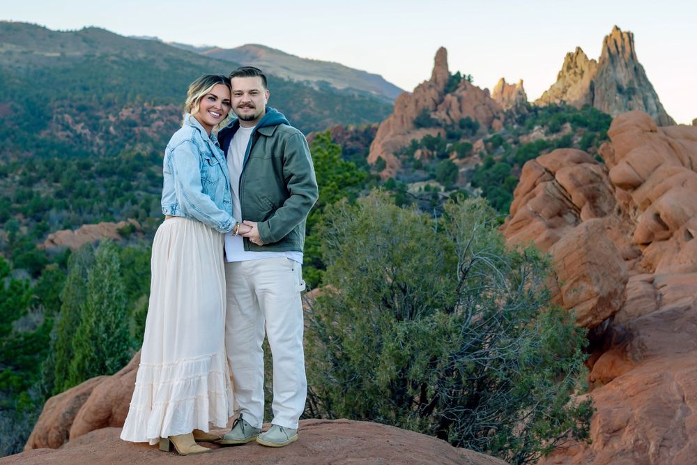 Couple poses on red rocks at Garden of the Gods during sunset wearing light colored clothing.
